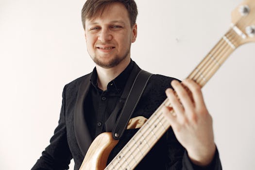 A man in formal attire playing a bass guitar, captured in a studio setting.
