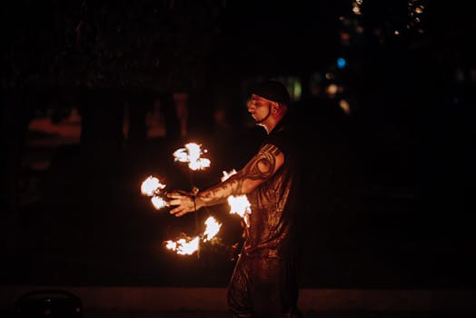 A captivating image of a male fire performer skillfully juggling flames in the dark.