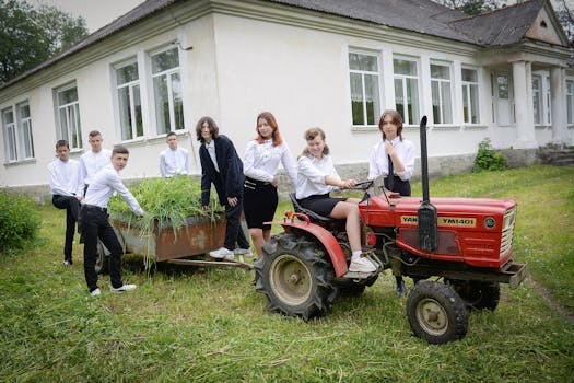 Students posing with a red tractor in a schoolyard, showcasing teamwork and education.