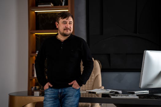 A man stands confidently by his desk in a stylish, modern office setting.
