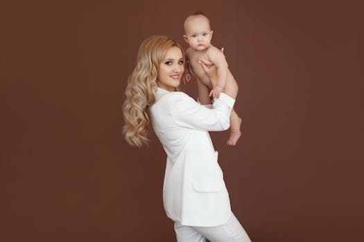 Charming studio portrait of a mother holding her baby, set against a brown background.