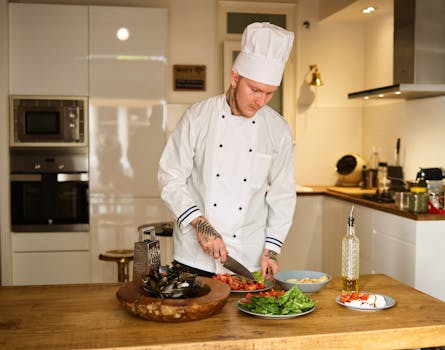 Professional chef slicing fresh vegetables in a modern kitchen, showcasing culinary skills.