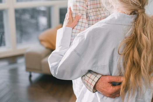 An intimate moment of a senior couple hugging indoors, captured in soft lighting.