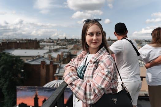 A young woman with sunglasses enjoys a rooftop view of a city skyline on a sunny day.