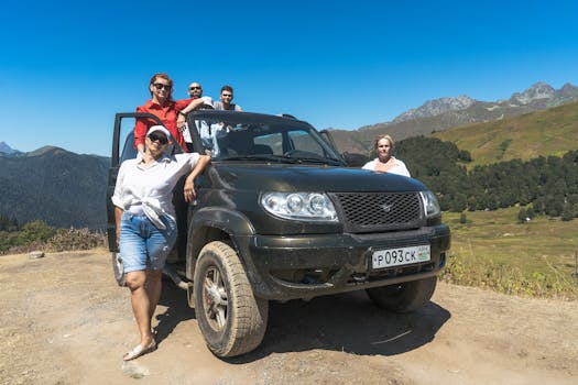 A group of adults posing with an SUV in the mountainous region of Gagra under a clear blue sky.