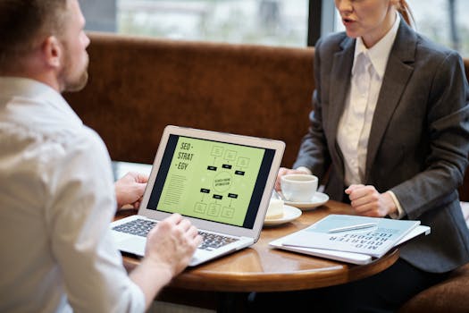 A man and woman engaged in a business meeting discussing SEO strategy in a cozy cafe setting.
