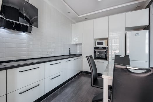 Sleek modern kitchen with white cabinets, black accents, and dining area.