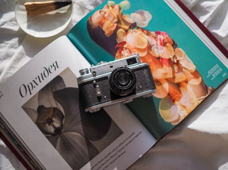 A vintage camera placed on an open magazine featuring artistic photography and colorful designs.