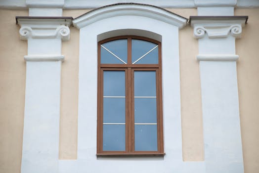 Elegant classical window surrounded by ornamental white columns and arch details on a facade.