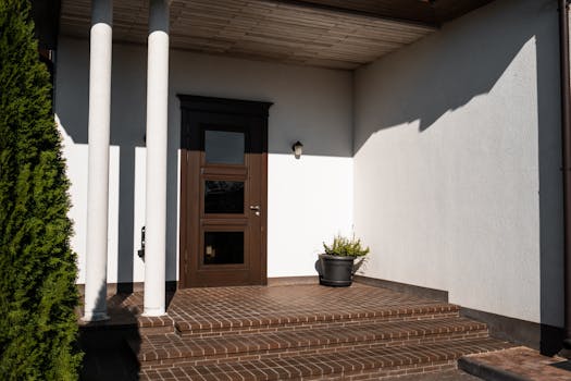Contemporary house entrance featuring brown door, brick steps, and decorative columns.