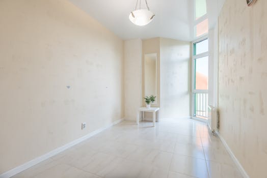 Empty room with tiled floor and potted plant on table near balcony door reflecting on stretch ceiling