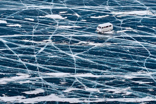 A van driving across the icy surface of Lake Baikal with intricate ice patterns.