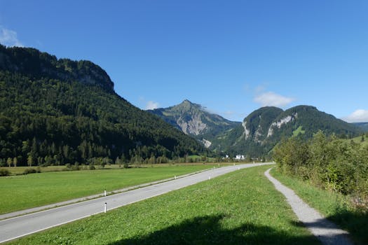 Breathtaking view of a valley surrounded by lush mountains under a clear blue sky.