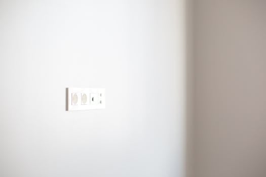 Close-up of a white wall featuring a modern electrical outlet, ideal for design concepts.