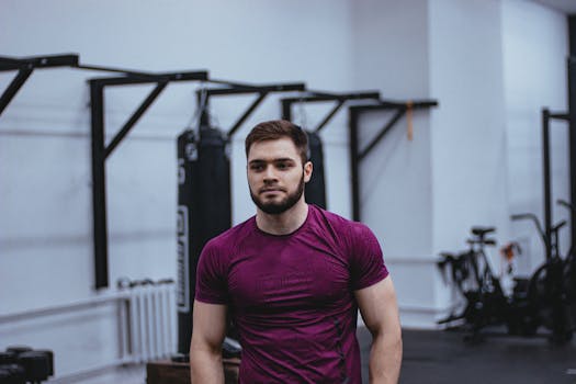 Caucasian man with beard working out in gym, wearing purple shirt, focused expression.