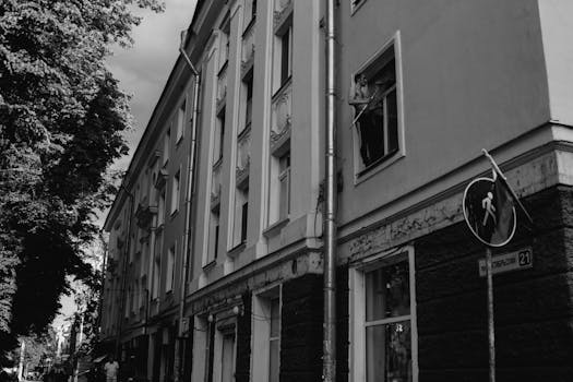 Monochrome image of an urban building exterior with man on the windowsill.