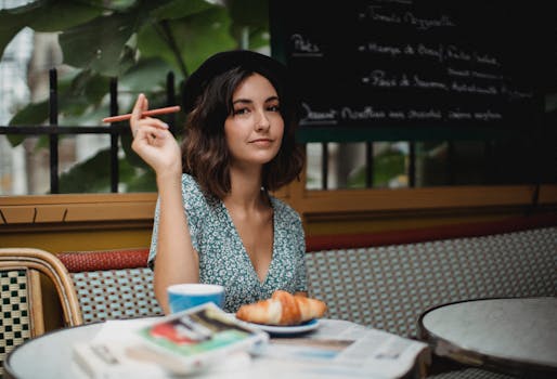 Chic woman in beret savors coffee and croissant at a cozy outdoor café, showcasing European elegance.
