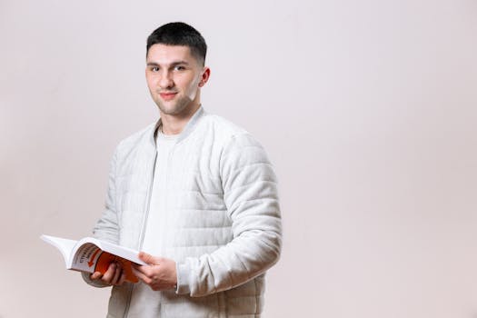 Portrait of a young man reading a book, exuding confidence and positivity in a studio setting.