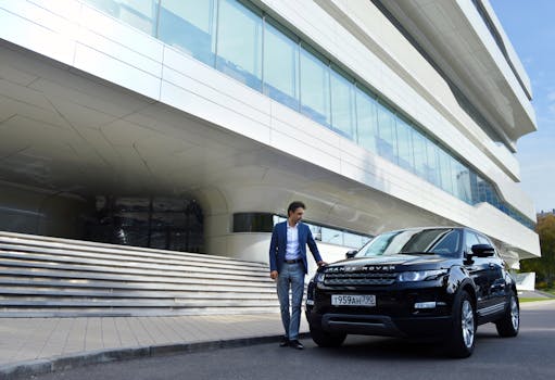 Full body young successful male in stylish wear standing near modern black car parked outside contemporary office building
